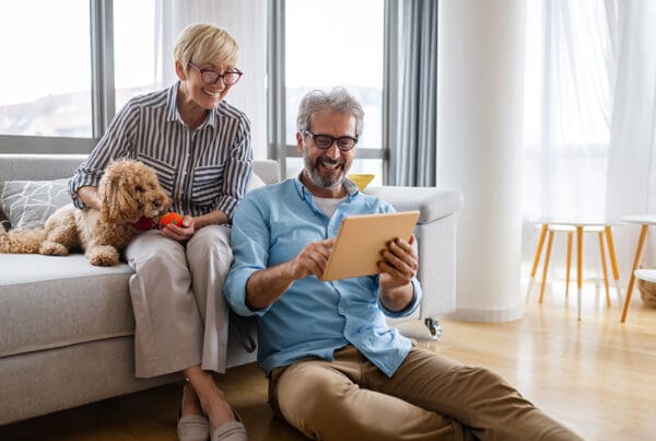 Contact - Senior Couple Sitting With Their Dog and Using Their Tablet